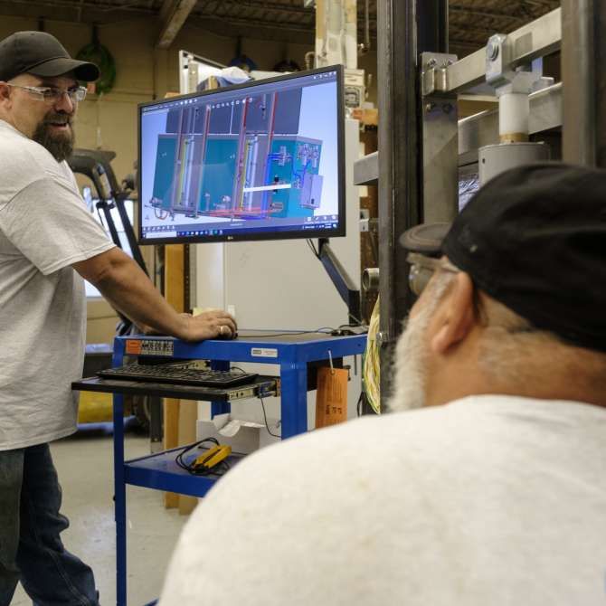 Man smiling in front of screen that has blueprint design displayed